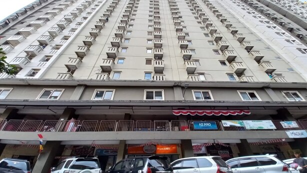 Un immeuble de grande hauteur doté de nombreux balcons et d’un espace commercial au rez-de-chaussée comprenant divers magasins.