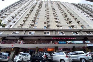 Een hoog gebouw met meerdere balkons en een commerciële plint met diverse winkels.