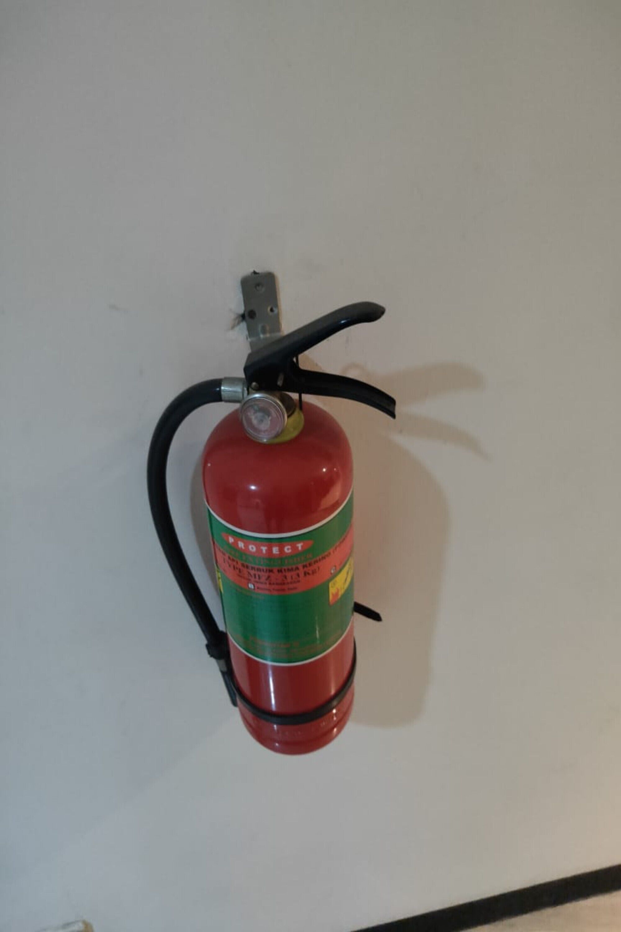 A red fire extinguisher mounted on a white wall.
