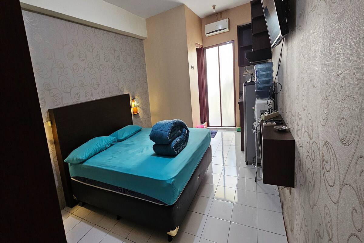 A hotel room with a bed, a desk, a water dispenser, and a TV.