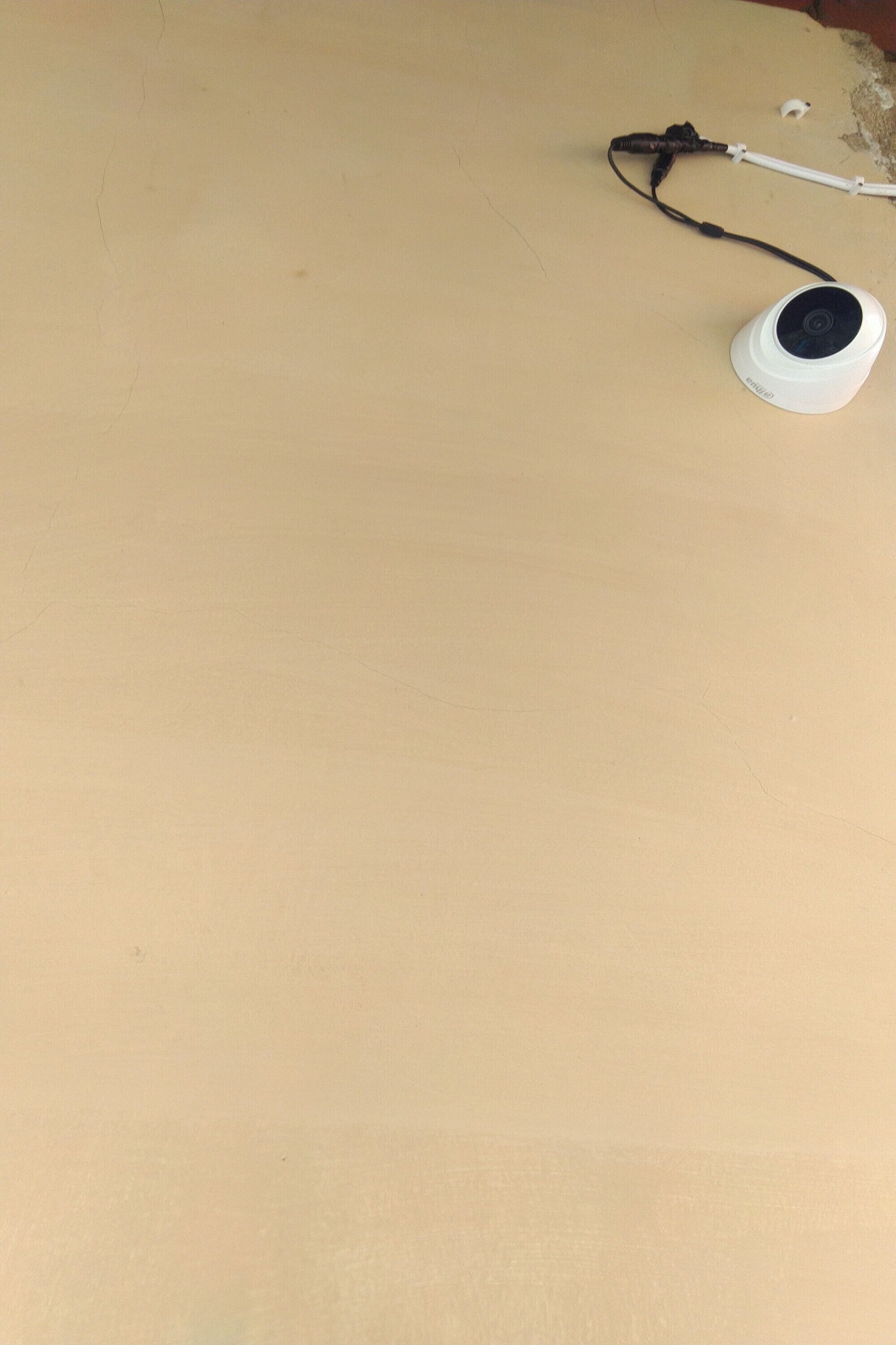 A white circular object with a black cord on a plain beige surface.