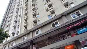 Un immeuble de grande hauteur doté de nombreux balcons et d’un espace commercial au rez-de-chaussée comprenant des boutiques.