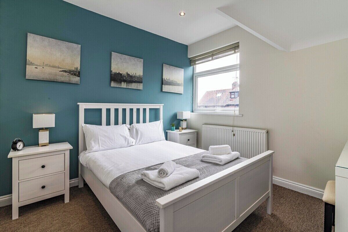 A bedroom with a bed, nightstands, a window, and artwork on the wall.