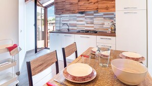 A modern kitchen with wooden cabinets, a tiled backsplash, and a dining area with a table set for two. - Cozy home in San Marco Castellabate with WiFi (San Marco Castellabate)