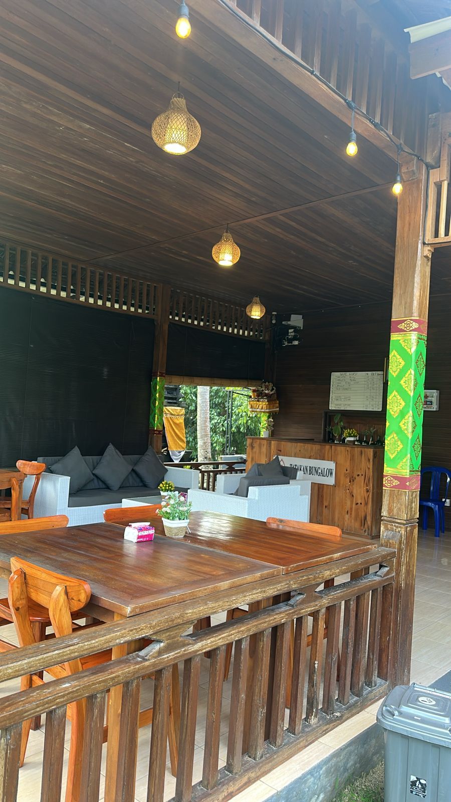 A wooden interior with a long dining table, cushioned seating, and hanging lights.