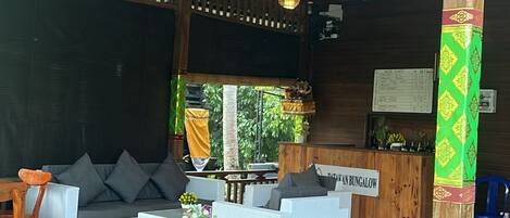 A wooden interior with a long dining table, cushioned seating, and hanging lights.