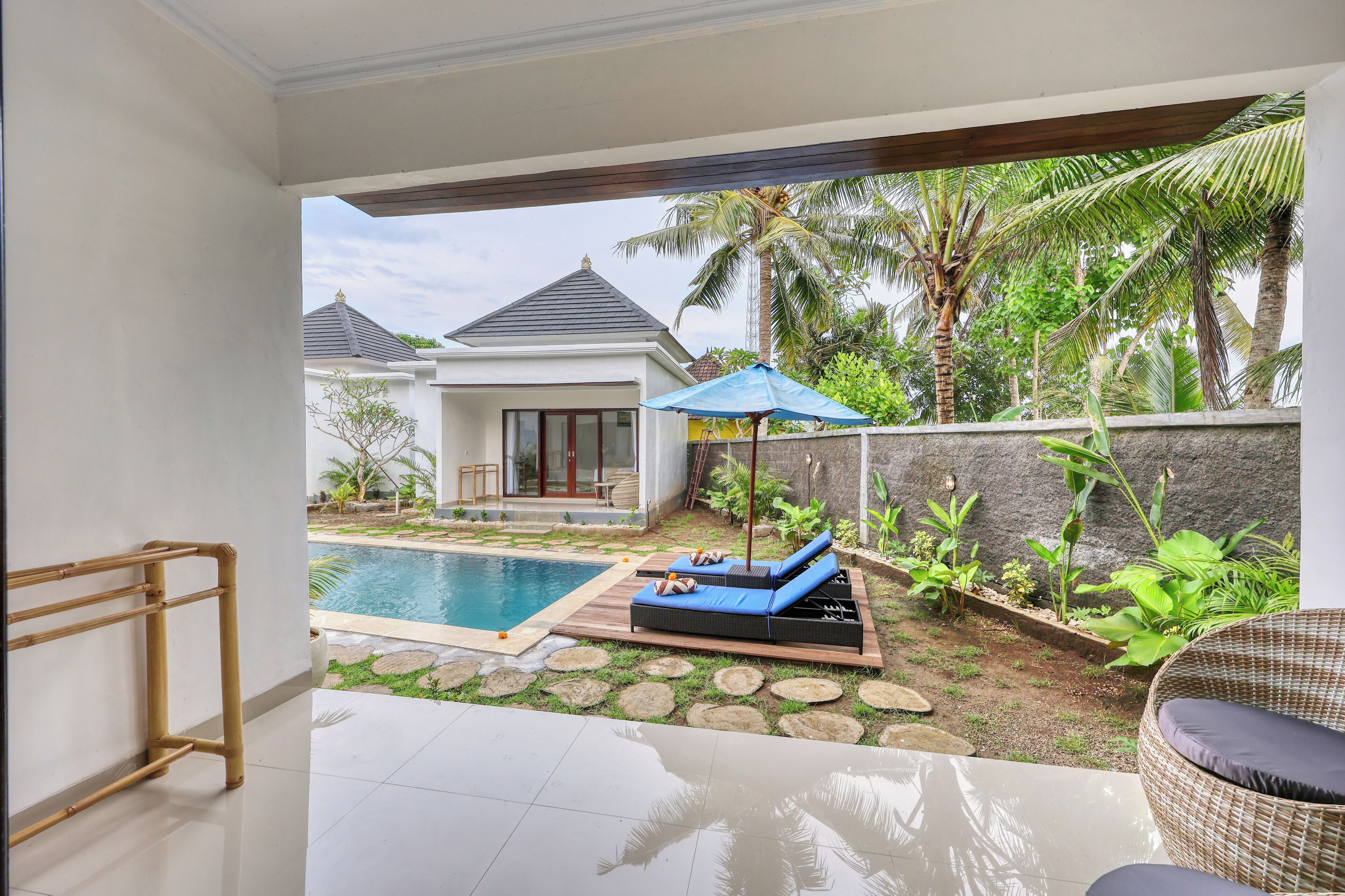 A poolside area with lounge chairs, a small pool, and a view of a house in the background.