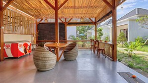A covered outdoor seating area with a bamboo roof, wicker furniture, and a buffet table.