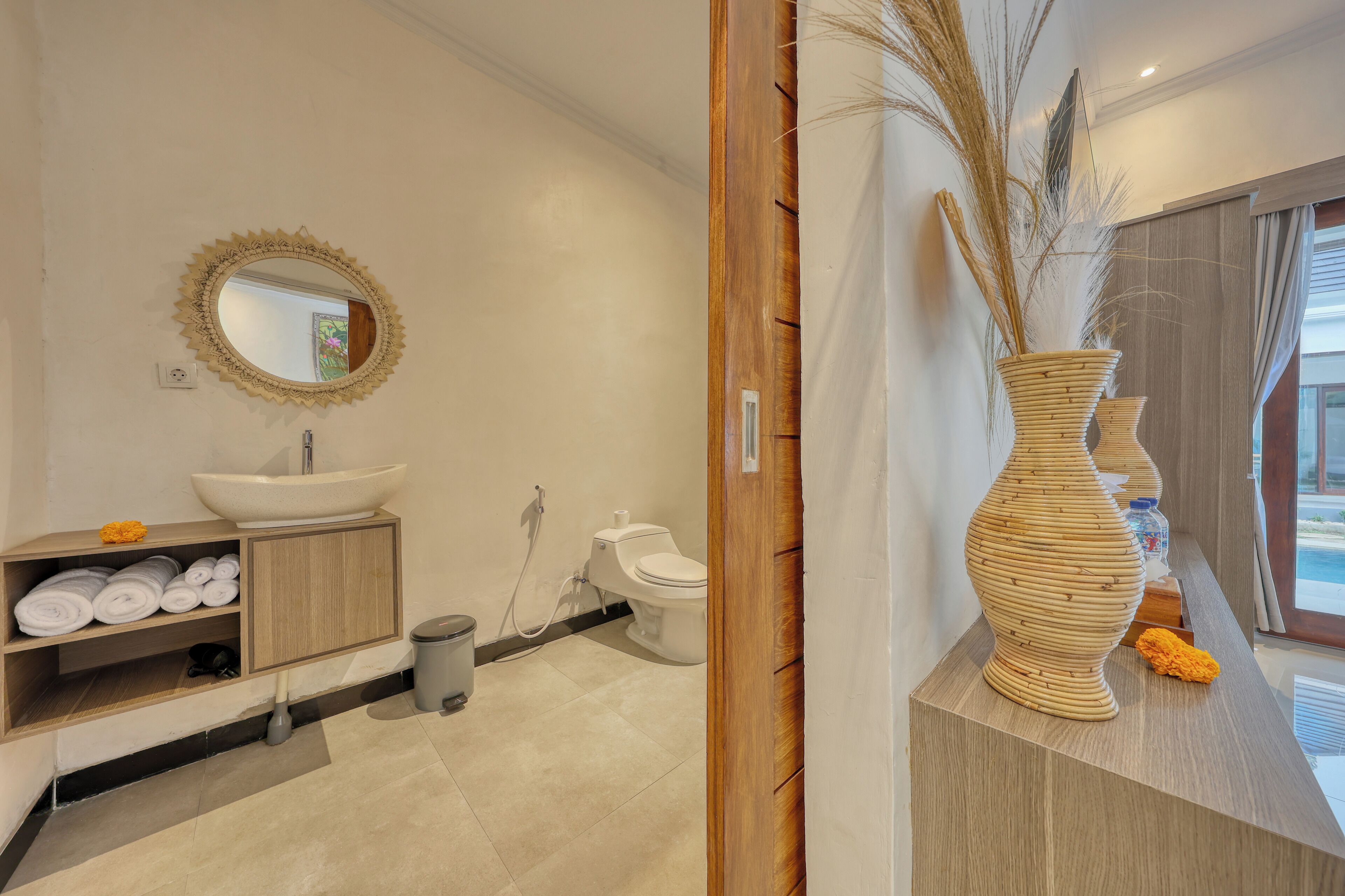 A modern bathroom with a large sink, toilet, and a decorative vase.