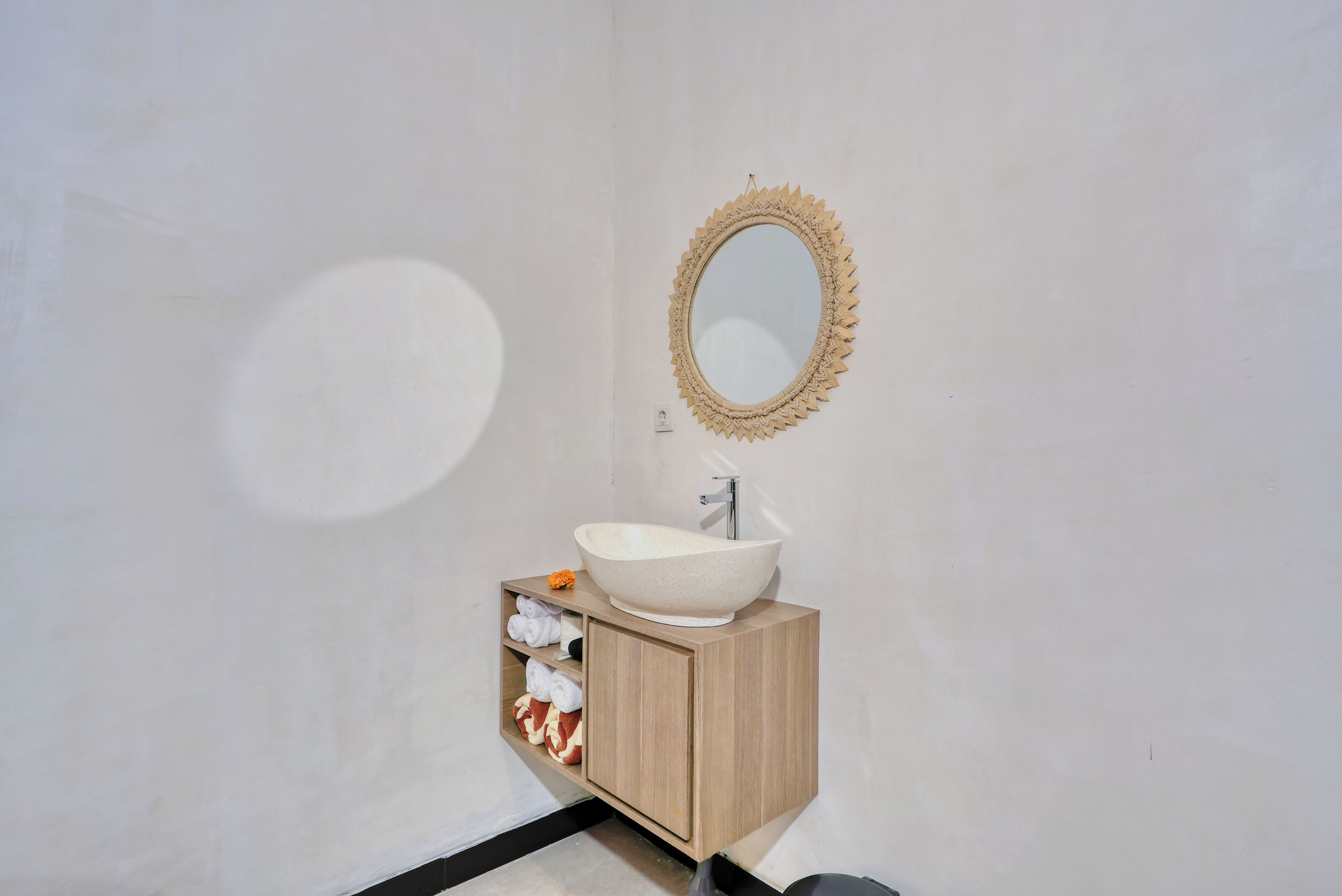 Un baño con un lavamanos blanco, un mueble de madera y un espejo decorativo.