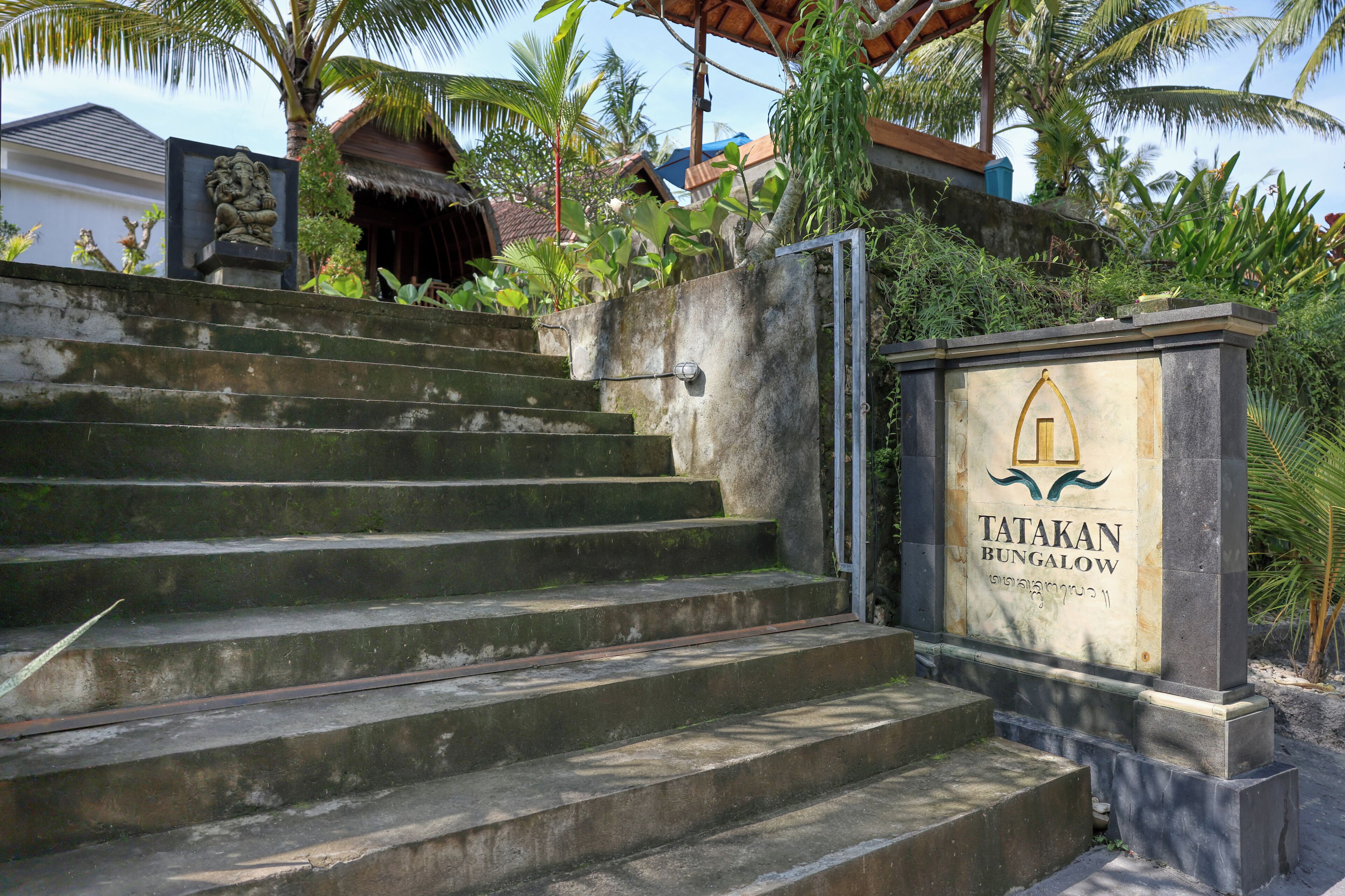 A set of concrete steps leading to a gated entrance with a sign reading "TATAKAN BUNGALOW."