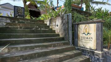 A set of concrete steps leading to a gated entrance with a sign reading "TATAKAN BUNGALOW."