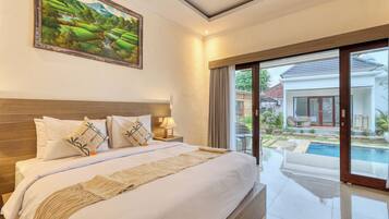 A hotel room with a large bed, a painting, a view of a swimming pool, and a balcony with outdoor furniture.