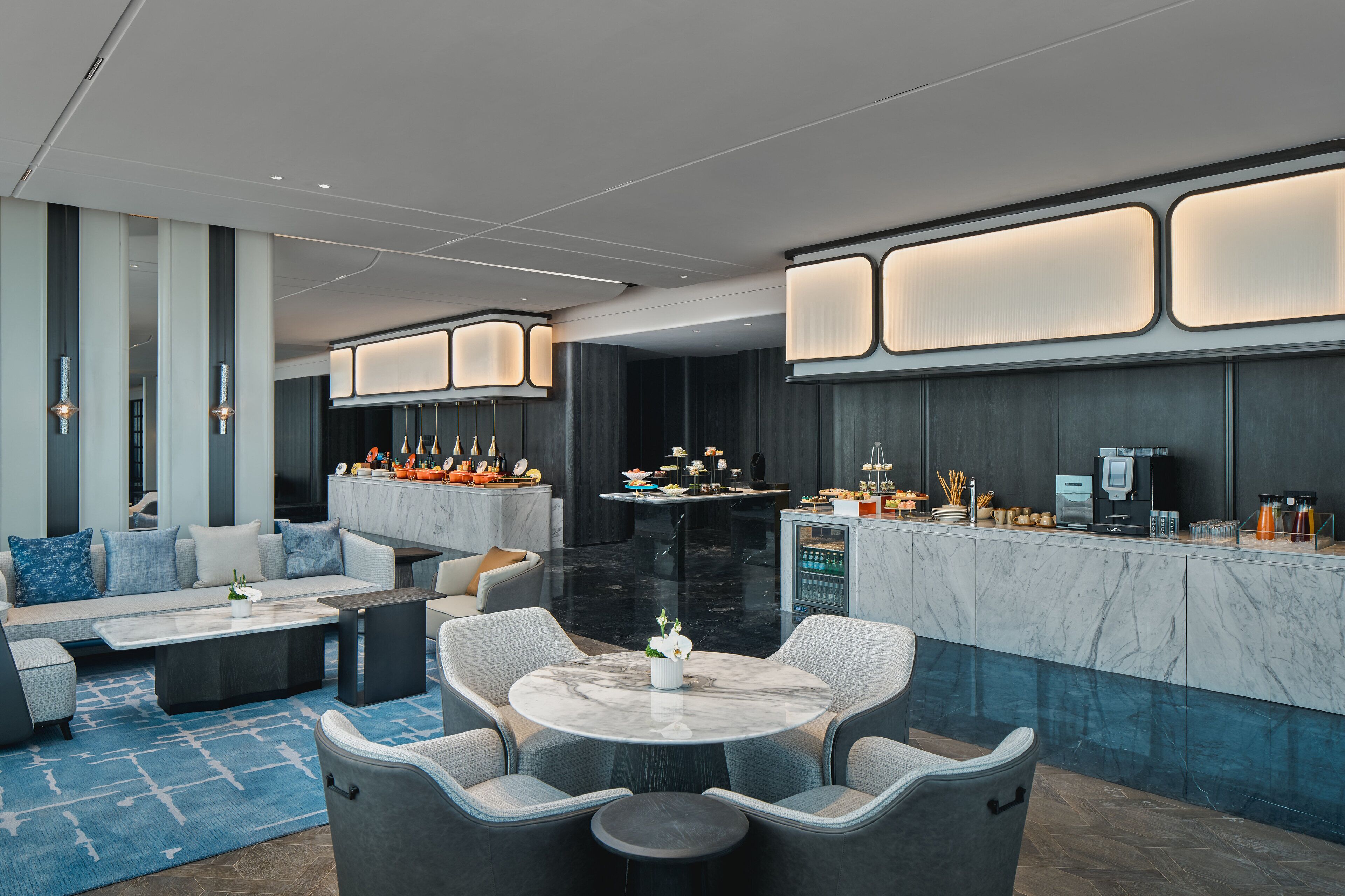 A modern hotel lobby with a seating area, a bar, and a reception desk.