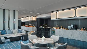 A modern hotel lobby with a seating area, a bar, and a reception desk.