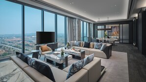Ein modernes Wohnzimmer mit großem Fernseher, bequemen Sitzgelegenheiten und Blick auf die Stadt.