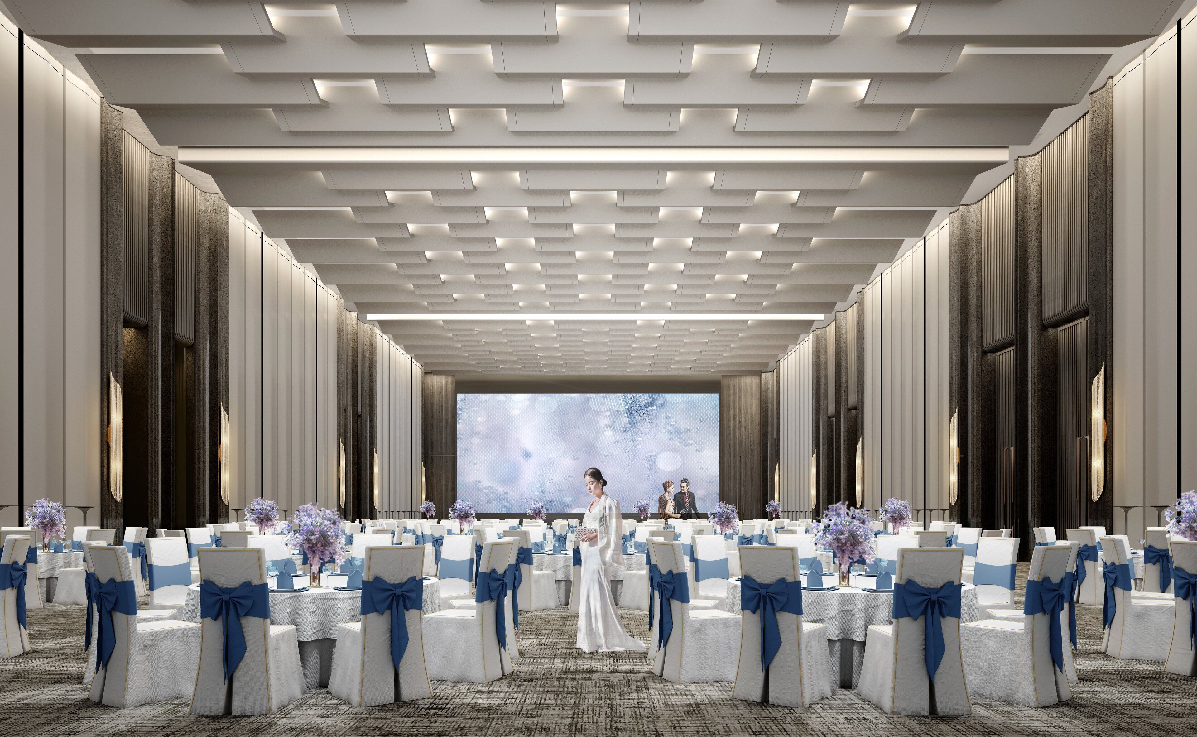 Un espacio para eventos formales con filas de sillas blancas con cintas azules, una pantalla grande al frente y un diseño de techo moderno.