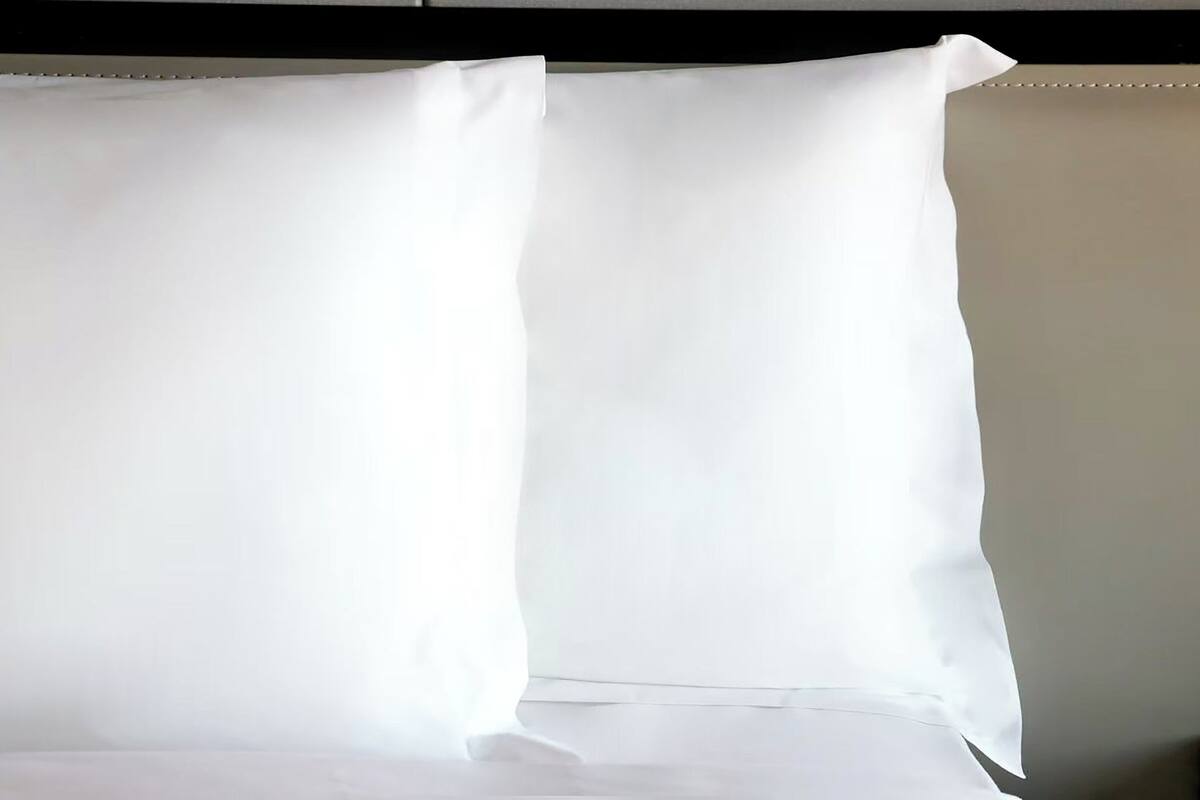 A room with a large white bed and a plain wall.