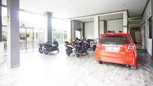A covered parking area with multiple motorcycles and a red car.