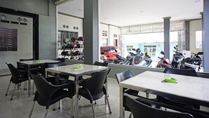 A dining area with tables and chairs, a view of parked motorcycles, and a red vehicle outside.