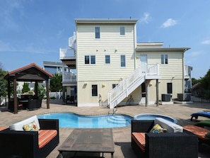 Um edifício de dois andares com piscina, área de estar ao ar livre e varanda coberta.
