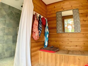 A wooden cabin bathroom with a shower, a mirror with a decorative frame, and a bench with a red towel. - 6 BR, Pool, Hot Tub and 5 min to Ocean (Loveladies)
