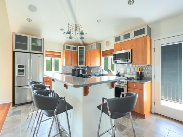 A modern kitchen with a central island, stainless steel appliances, and wooden cabinetry. - 6 BR, Pool, Hot Tub and 5 min to Ocean (Loveladies)