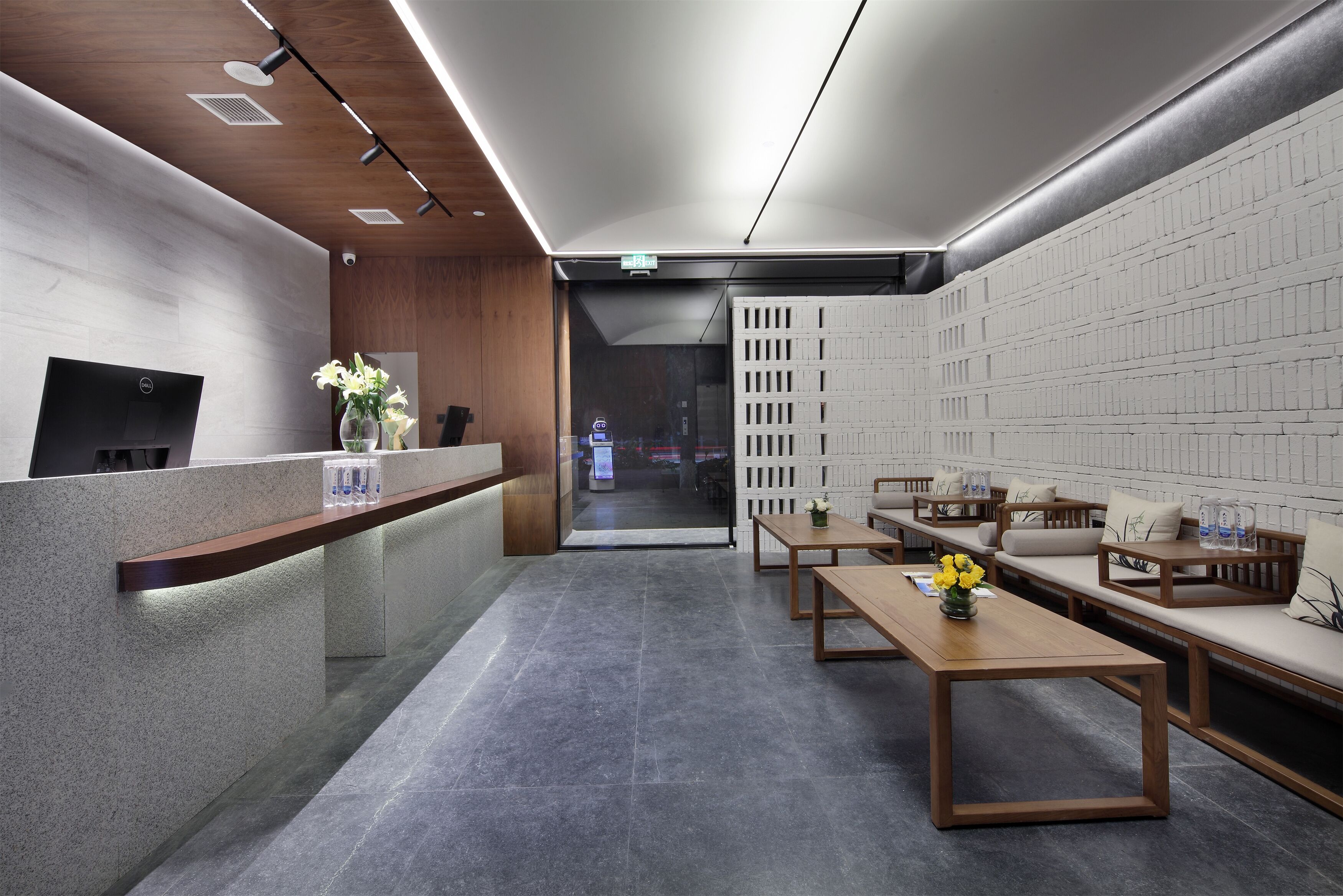 Een moderne receptiezone met een receptiebalie, een zithoek en uitzicht op de lobby.