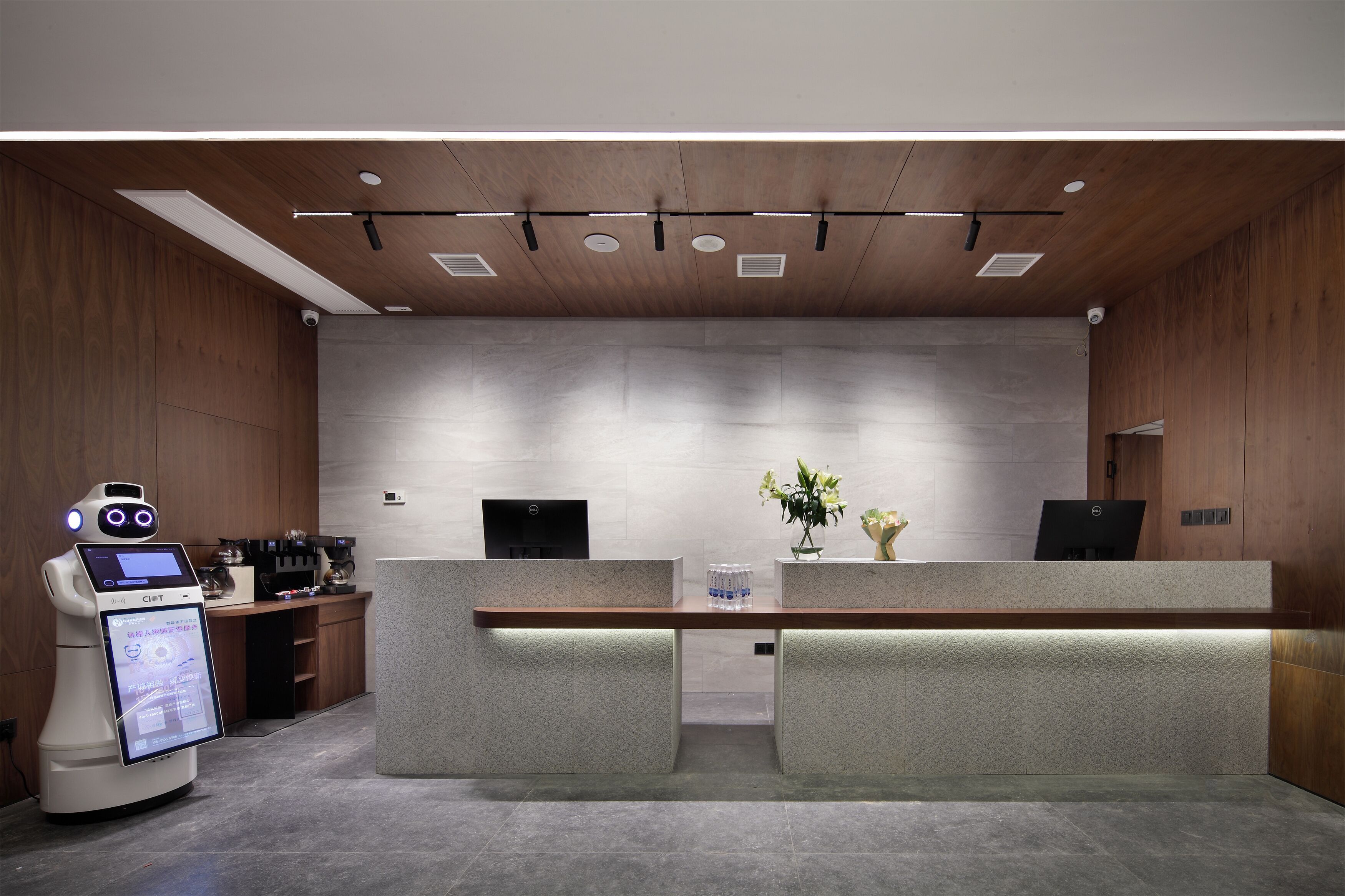 A modern reception area with a robot, a reception desk, and a coffee machine.
