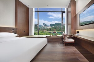 Una habitación de hotel moderna con una cama grande, un escritorio y vistas a un paisaje montañoso.