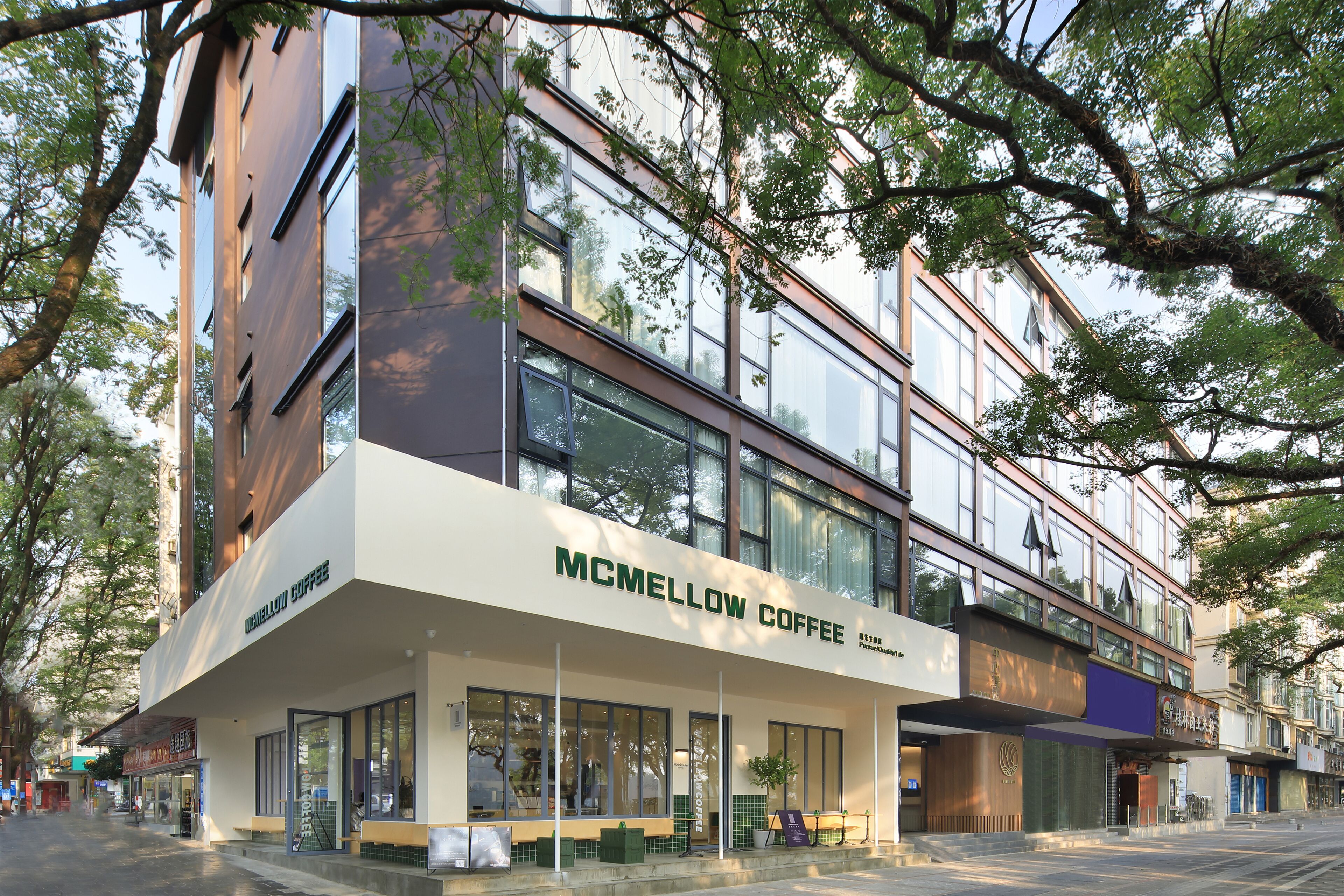 Um edifício moderno com uma cafeteria chamada "MCMELLOW COFFEE" no andar térreo.