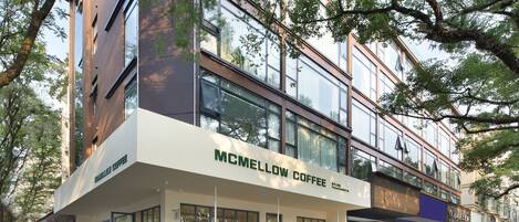 Um edifício moderno com uma cafeteria chamada "MCMELLOW COFFEE" no andar térreo.