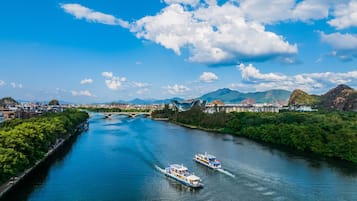 A river with boats, a bridge, and a cityscape with mountains in the background.