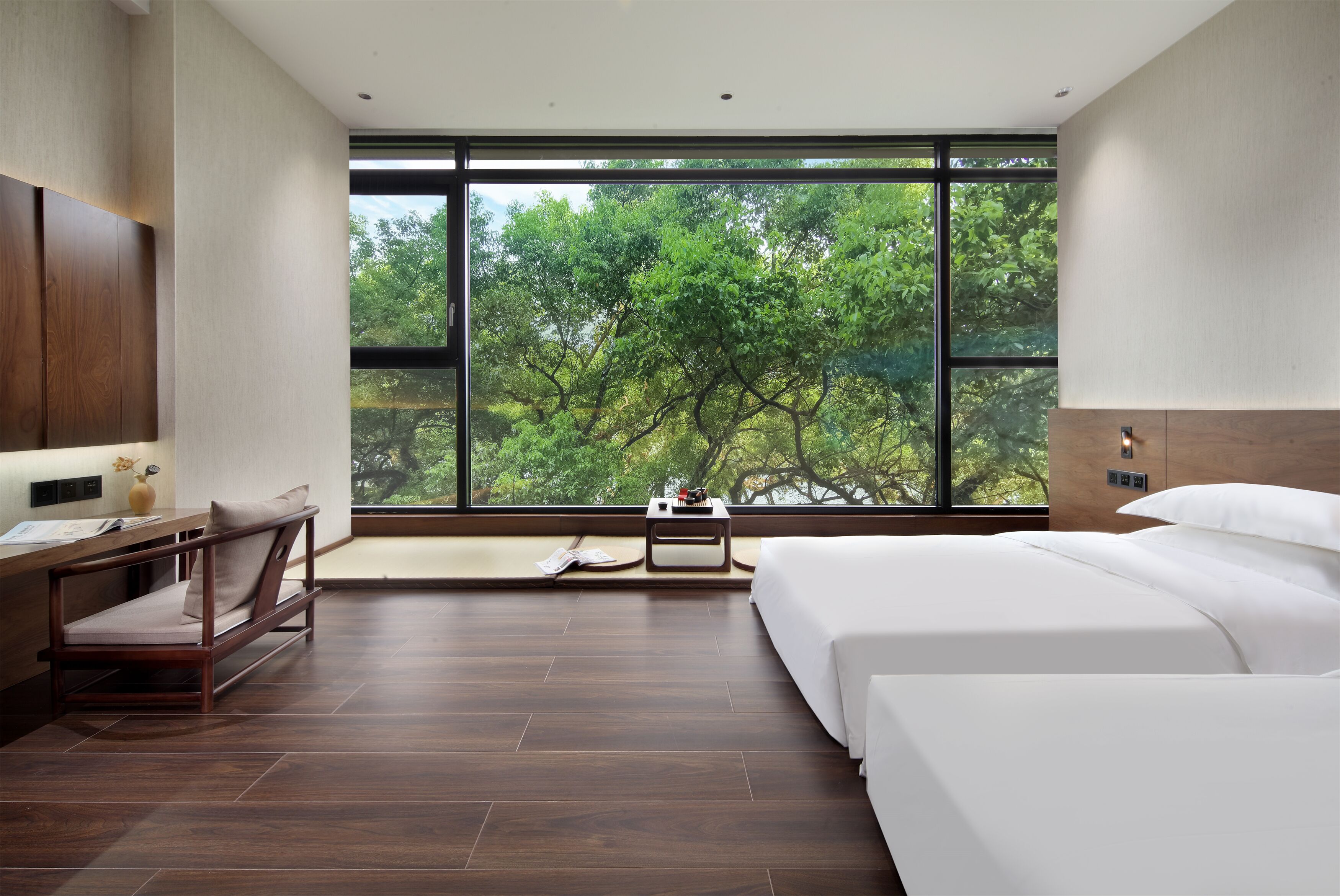 Una habitación de hotel moderna con un amplio ventanal, una cama, un escritorio y una silla.