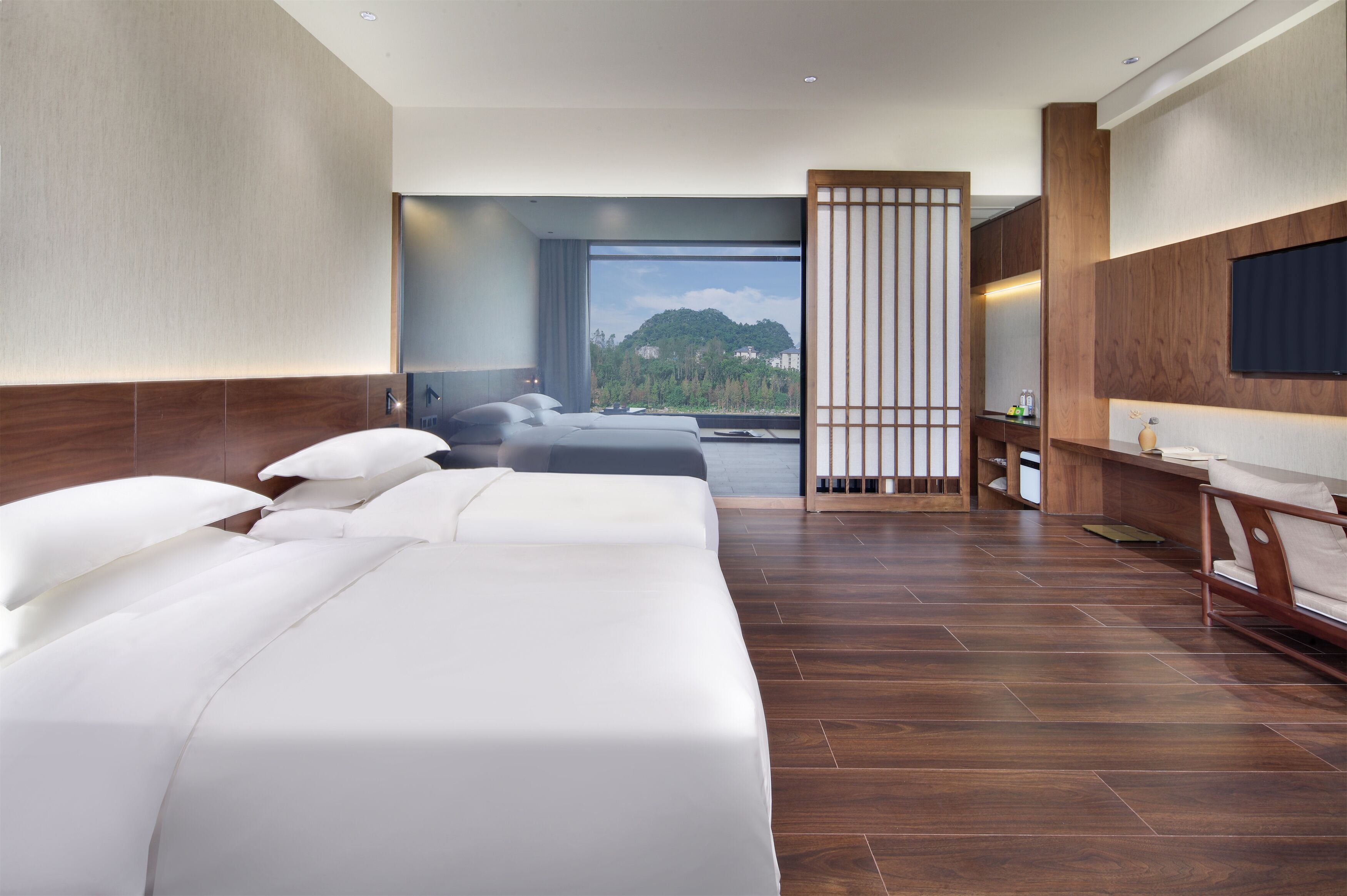 A hotel room with a large bed, a TV, and a view of a mountain.