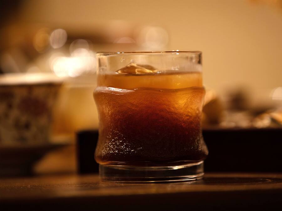 A glass of iced tea on a table with a blurred background.