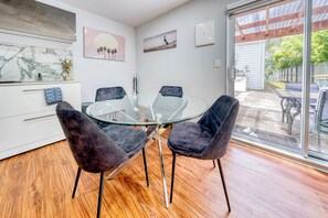 A modern dining area with a glass table and dark chairs, a white cabinet with drawers, and artwork on the walls. - Auckland's Urban Escape - Central, Connected & Comfortable (Auckland)