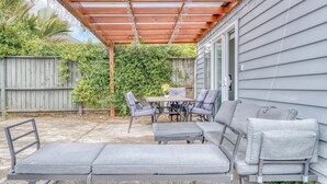 Un patio couvert avec une table et des chaises, un banc et une pergola en bois.