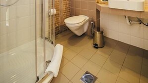 Une salle de bain moderne avec une douche à parois de verre, des toilettes blanches et un lavabo surmonté d’un miroir.