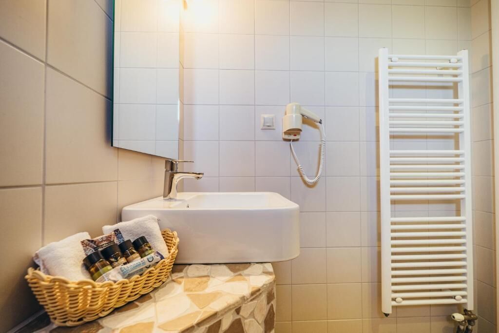 A bathroom with a white sink, a mirror, a towel rack, and a wall-mounted hairdryer.