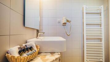 A bathroom with a white sink, a mirror, a towel rack, and a wall-mounted hairdryer.