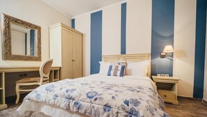 Une chambre à coucher comprenant un lit, un bureau, une chaise, une armoire et une table de chevet.