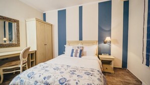 Une chambre à coucher comprenant un lit, un bureau, une chaise, une armoire et une table de chevet avec une lampe.