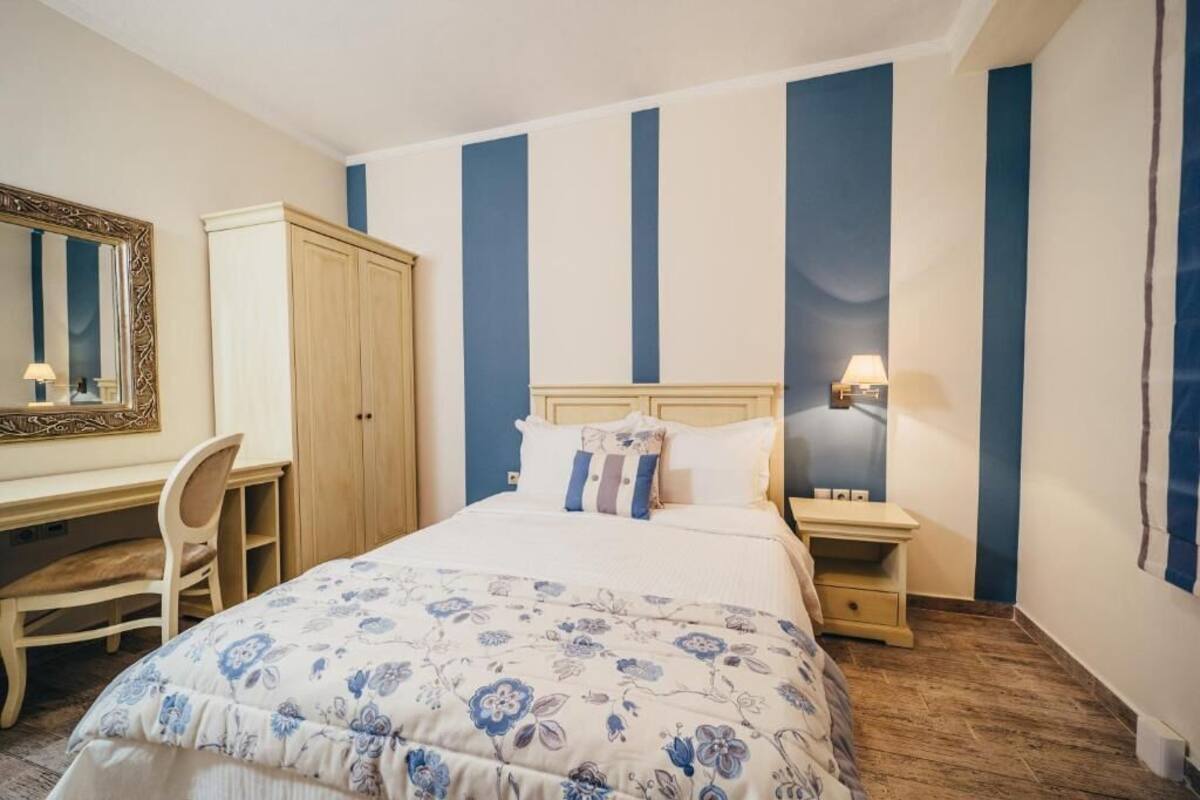 Une chambre à coucher comprenant un lit, un bureau, une chaise, une armoire et une table de chevet avec une lampe.