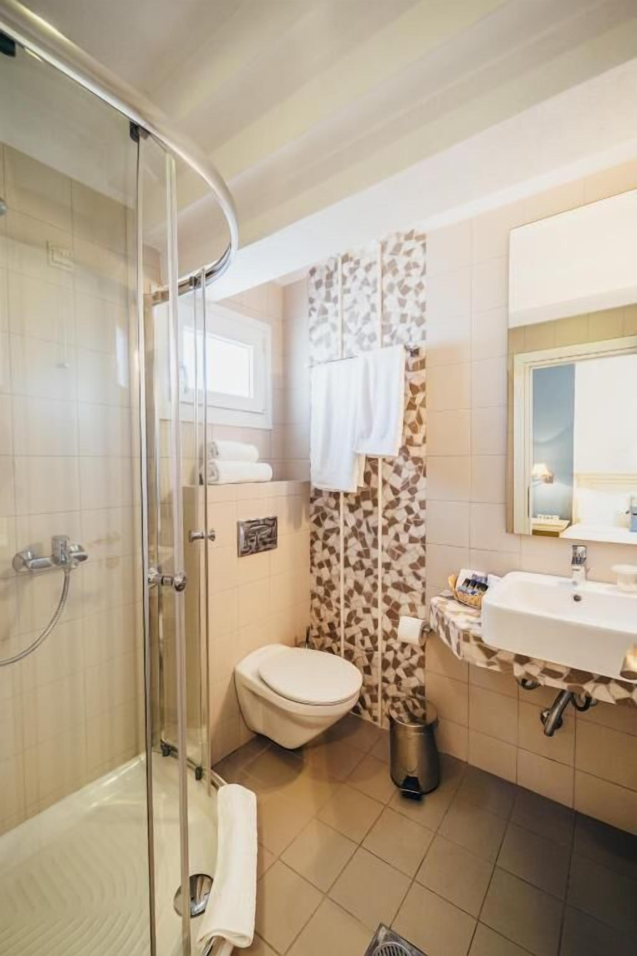 Ein Badezimmer mit Duschkabine, Toilette, Waschbecken und Spiegel.