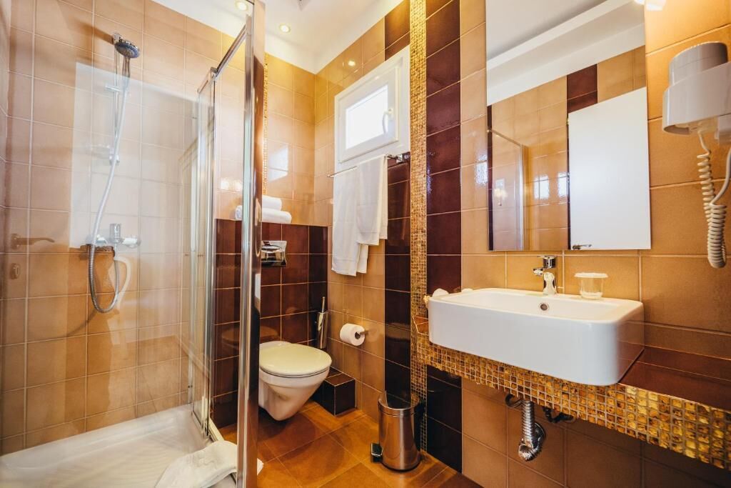 A modern bathroom with a glass-enclosed shower, a toilet, and a sink with a mirror above it.