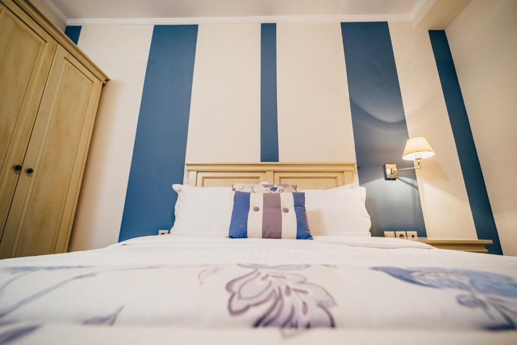 A hotel room with a bed, a nightstand, a lamp, and a wardrobe.