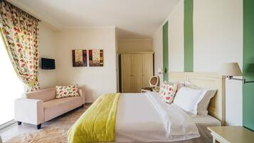 Une chambre d’hôtel avec un lit, un canapé, une télévision et des œuvres d’art accrochées au mur.