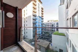 Een balkon met uitzicht op een modern gebouwcomplex, met meerdere balkons en een glazen balustrade.