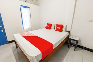 Una habitación de hotel con una cama, una mesita de noche, un ventanal con cortinas azules y una puerta.